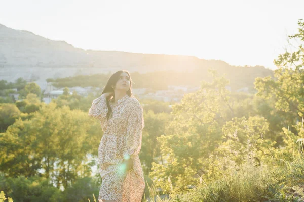 La mujer está mirando a lo lejos en la colina. La morena está al sol —  Fotos de Stock