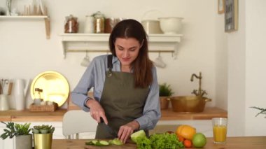 Güzel bir kadın, sıcak, ahşap bir mutfakta kahvaltı hazırlıyor. Genç bir kadın elmadan bir ısırık alır ve kameraya bakar.