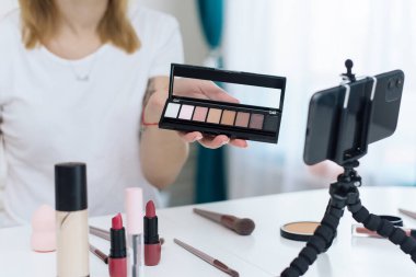 Kadın video blogcusu yüzüne nasıl kozmetik uygulanacağını gösteriyor. Hayvansal olmayan kozetikler hakkında konuşmak için harika bir kadın etkileyicidir.
