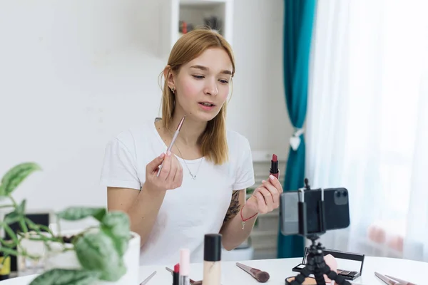 Seminarios web de belleza, clases de maquillaje en línea. Happy woman vlogger está mostrando productos de cosméticos mientras graba transmisión de video en el teléfono para su canal de Internet en las redes sociales. blog de belleza sobre cosméticos — Foto de Stock