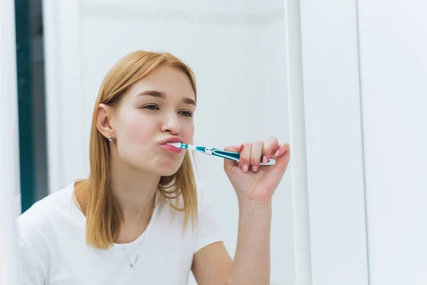 Mujer joven limpiando dientes con cepillo de dientes en el baño. Higiene oral — Foto de Stock