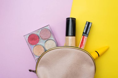 Pembe ve sarı arka planda pembe bir kozmetik çantadan dekoratif kozmetik seti. Kopyalama. Makyaj sanatçıları güzellik uzmanı