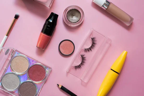 Dekorativ kosmetika på en rosa bakgrund. Läppstift, puder, ögonskugga och foundation för ljus makeup. Skönhet, mode och shopping koncept — Stockfoto