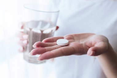 Eller bir bardak su ve ağrı kesici tutar. Sağlık sigortası, tıbbi destek konsepti. Ağrı kesicili kadına yaklaşın.