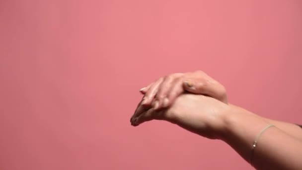 A woman washes her hands with soap in the studio on a pink background. Close-up — Stock Video