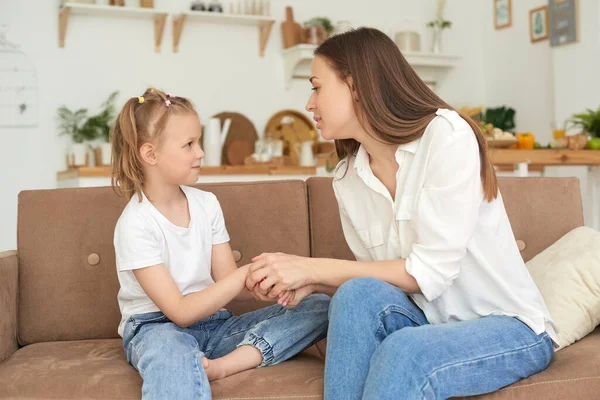 Das kleine Mädchen beschwert sich bei seiner Mutter und weint. Eine junge Frau beruhigt ihre Tochter auf dem heimischen Sofa — Stockfoto