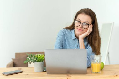 Öğrenci evde dizüstü bilgisayarla karmaşık bir ödev yaparken düşünüyor. Genç ve güzel iş kadınının fotoğrafı ofiste dizüstü bilgisayarla oturup düşünceli bir şekilde havaya bakıyor.