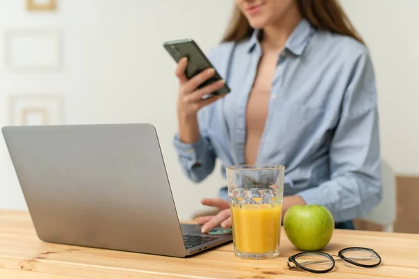 Happy beautiful young woman, sitting at the table at home, taking courses on the Internet and conducting a live broadcast. Work and study from home under quarantine conditions