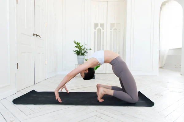 Ung kvinna som utövar yoga i en ljus bakgrund. Friska livsstil koncept — Stockfoto