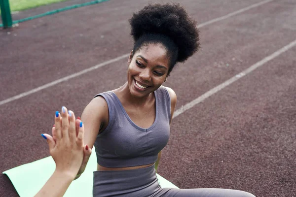 Deux petites amies africaines et iraniennes différentes se donnent cinq pendant l'exercice. Sports jeunes femmes acclamant à l'extérieur ensemble pour des cours de conditionnement physique dans la rue. Gros plan — Photo