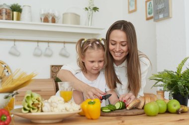 Anne, kızlarını sebze keserken kontrol ediyor. Aşçılık eğitimi