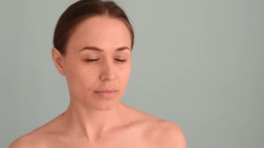 Gülümseyen kadın mavi arka planda yüzüne dokunuyor. Doğal güzellik konsepti, mutlu kadın.