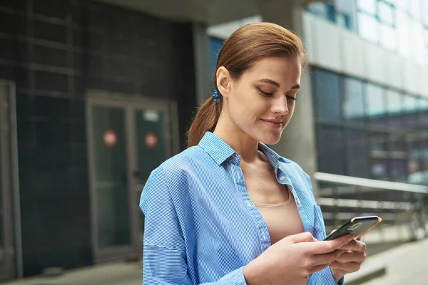 Успешная молодая деловая женщина проверяет электронную почту на смартфоне во время обеденного перерыва за пределами офиса. Городская предпринимательница — стоковое фото