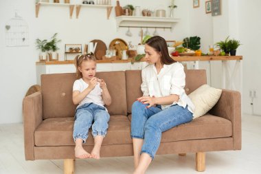 Anne ve kızının güven ilişkisi. Mutfaktaki kanepede küçük bir kızla bir kadının konuşması. En iyi arkadaşlar, çocuk konseptiyle annelik hafta sonunuz kutlu olsun.
