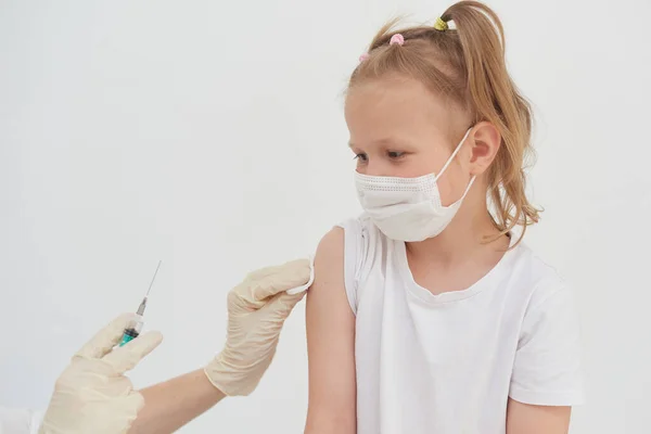 A little girl is afraid of vaccinations, injections and vaccinations. The child is being vaccinated against the coronavirus