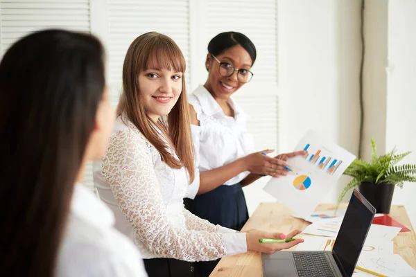 Smiling women work together in a modern office. Feminism. Professional smiling business women standing in the office and discussing business papers