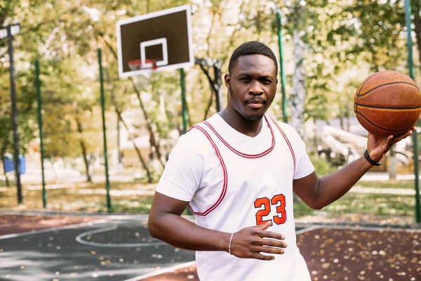 Afrikai amerikai kosaras egy szabadtéri sportpályán, aki egy labdával játszik. sportol az utcán. — Stock Fotó