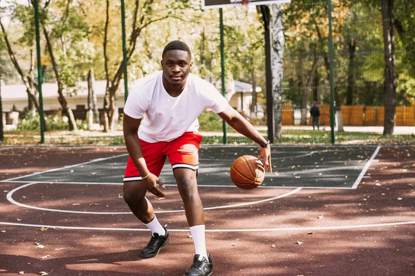 Afrikai amerikai kosaras egy szabadtéri sportpályán, aki egy labdával játszik. sportol az utcán. — Stock Fotó