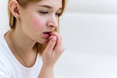 Genç bir kadın yatakta oturur, endişelenir ve tırnaklarını yer. Endişeli kadın yatak odasında yatağında oturuyor.