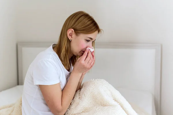 Sick millennial woman feeling bad, weak fight against flu, runny nose, rest at home, health problem concept. The woman blows her nose into a handkerchief. depression, sadness and crying