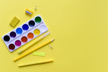 Boya, kalem ve makas. Sarı arka planda okul aksesuarları. Yukarıdan görüntüle