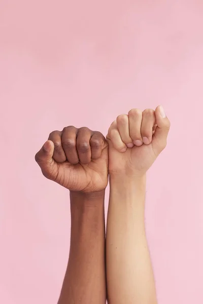 Fehér kaukázusi kéz és fekete etnikum kéz ökölbe szorítva rózsaszín alapon. Multiracionális tisztelet és megértés — Stock Fotó