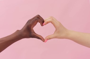 Beyaz kadın ve Afro-Amerikalı erkek ellerini pembe arka planda tutarak kalplerini gösteriyorlar. Irkçılık, hoşgörü kavramı