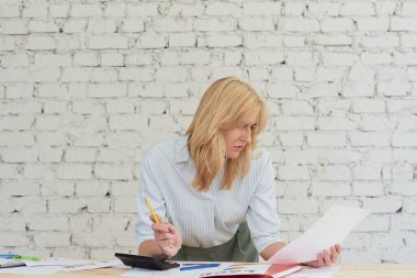 Güzel, gündelik kıyafetler içinde genç bir kadın çizelgelerle çalışıyor ve ofiste dururken gülümsüyor. Ofiste çalışan kadın direktör elinde çizelgeler tutarken iş istatistiklerini analiz ediyor.