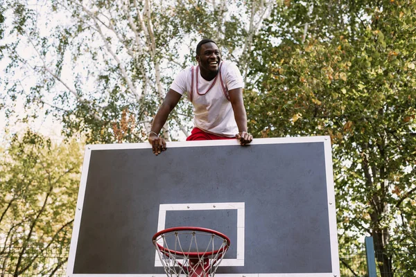 Portré egy jóképű fekete fiatalemberről, aki kosárlabdát tart a kosárpályán. Tarts szünetet edzés közben. Divatos sport portré — Stock Fotó