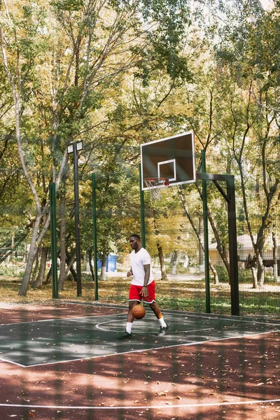 Young black smiling man playing basketball on the court at sunrise, morning sports. Outdoor portrait — Stock Photo, Image