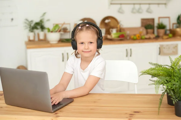 Educación en línea para niños. Una colegiala mira a la cámara mientras estudia usando un portátil desde casa. Cuarentena — Foto de Stock