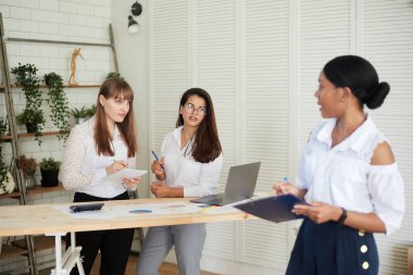 Gülümseyen kadınlar modern bir ofiste birlikte çalışırlar. Feminizm. Profesyonel gülümseyen iş kadınları ofiste duruyor ve iş belgelerini tartışıyorlar.