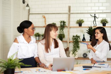 Gülümseyen kadınlar modern bir ofiste birlikte çalışırlar. Feminizm. Profesyonel gülümseyen iş kadınları ofiste duruyor ve iş belgelerini tartışıyorlar.