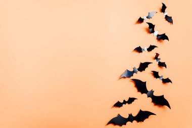 Turuncu arka planda suni yarasalar. Cadılar Bayramı konsepti Düz konum, üst görünüm, kopyalama alanı