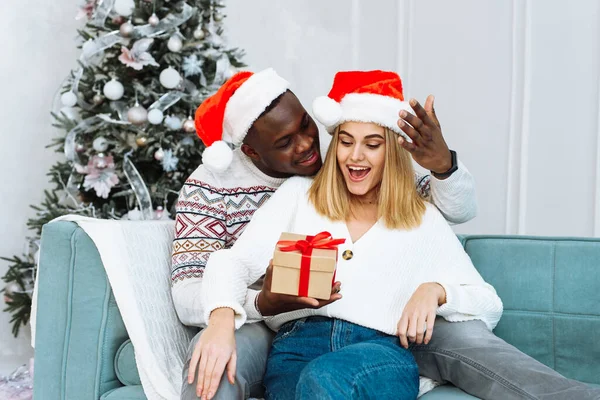 Una mujer se sorprende por el regalo que su marido le dio. Pareja compartiendo regalo de Navidad. Retrato de pareja encantadora en época de Navidad —  Fotos de Stock