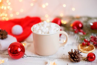 Noel arkaplanı, kahve fincanı ve şekerlemeler, kırmızı Noel oyuncakları, parlayan ışıklar. Mutlu Noeller tebrik kartı.