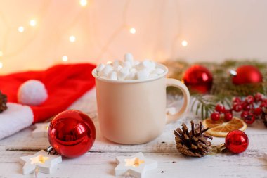 Noel arkaplanı, kahve fincanı ve şekerlemeler, kırmızı Noel oyuncakları, parlayan ışıklar. Mutlu Noeller tebrik kartı.