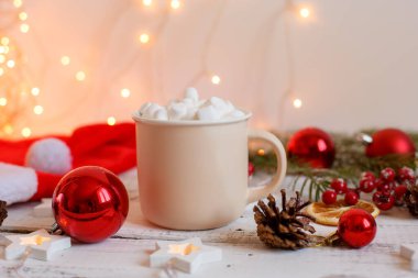 Noel arkaplanı, kahve fincanı ve şekerlemeler, kırmızı Noel oyuncakları, parlayan ışıklar. Mutlu Noeller tebrik kartı.