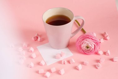 Kupa şeklinde marşmelov, gül ve kağıt dolu çay.