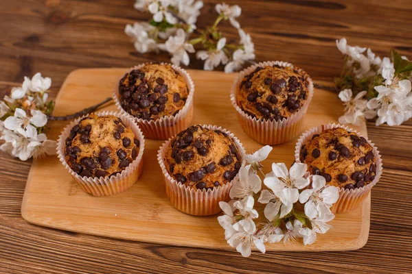 muffins with chocolate chips and a Cup of coffee on a wooden background with a blooming twig