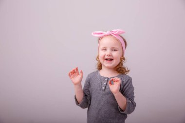 Sarışın kız farklı duygular gösteriyor. Şaşırtıcı. Gri bir arka planda sevinç.