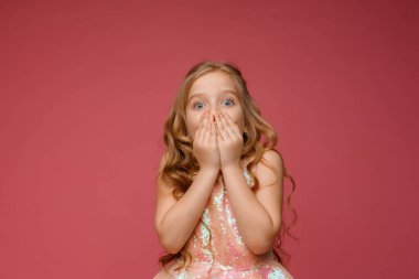 Pembe arka planda kıvırcık saçlı şirin bir kızın portresi.