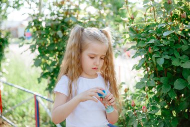 Bir kız yazın parkta sabun köpüğü üflüyor.