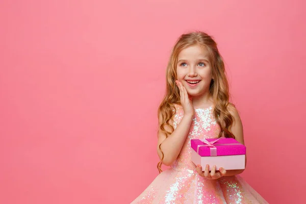 Seorang Gadis Kecil Memegang Hadiah Tangannya Tersenyum Pada Latar Belakang — Stok Foto