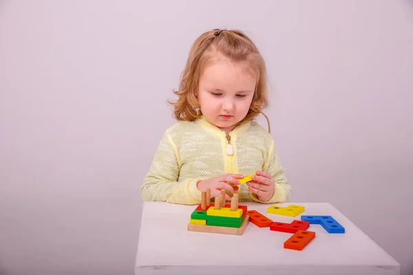 一个可爱的金发小女孩在一个白色背景的建筑商里玩耍 学前教育的概念 — 图库照片