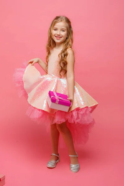 Uma Menina Segurando Presente Suas Mãos Sorri Fundo Rosa — Fotografia de Stock