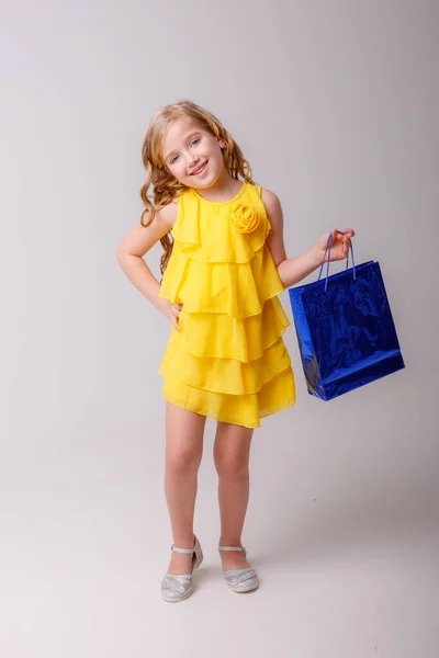 Niña Vistiendo Vestido Amarillo Sosteniendo Bolsa Compras Posando Estudio — Foto de Stock