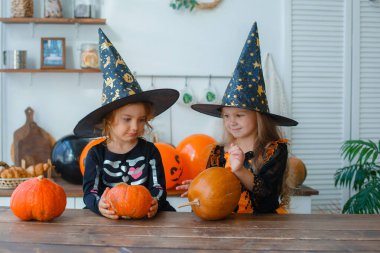 Cadılar Bayramı kostümü giymiş iki küçük kız stüdyoda poz veriyor.