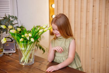 Vazonun yanında lalelerle poz veren güzel kız.