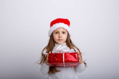 Noel Baba şapkasıyla ve hediye kutusuyla poz veren sevimli çocuk.